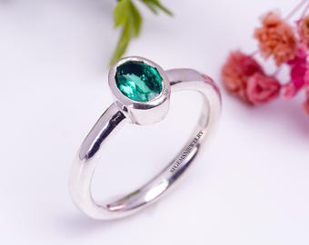 May include: A silver ring with a green oval gemstone set in a bezel setting. The ring is engraved with "SGEMS JEWELRY".