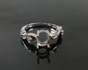 Puede incluir: Un engaste de anillo de plata con una piedra central de forma ovalada y cuatro piedras redondas más pequeñas engastadas a lo largo de la banda.