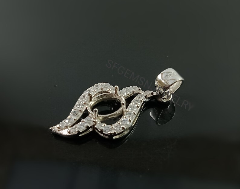 Puede incluir: Pendiente de plata con un engaste en forma de l&aacute;grima rodeado de piedras transparentes. El pendiente tiene un aro para sujetarlo a una cadena.