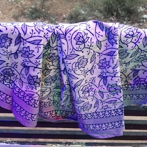 Puede incluir: Una tela blanca con un patrón floral azul. La tela tiene un borde azul claro con un diseño geométrico blanco y azul.