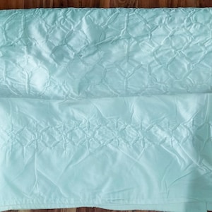 May include: A light blue quilted bedspread with a diamond pattern.