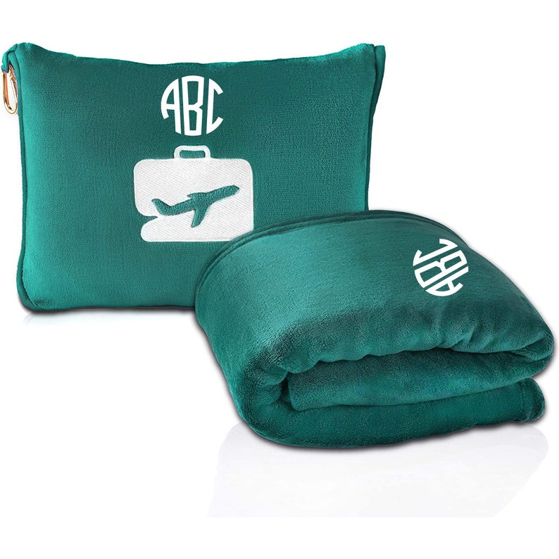 Puede incluir: Una manta de viaje de color turquesa con una almohada a juego. La almohada tiene un dise&ntilde;o blanco de avi&oacute;n y maleta con las letras "ABC" bordadas en un c&iacute;rculo. La manta tambi&eacute;n tiene las letras "ABC" bordadas en un c&iacute;rculo.