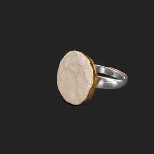 Peut inclure: Une bague en argent avec une pierre ronde blanche sertie dans une bande dorée.