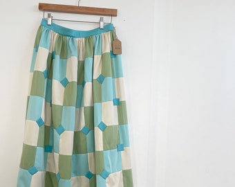 May include: A long, flowing skirt with a patchwork design. The skirt is made of a variety of fabrics in shades of green, blue, and white. The skirt has a wide waistband and a gathered hem.