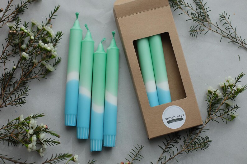 May include: Set of four ombre candles in shades of blue and green. The candles are packaged in a brown box with a white label that says "rumah saya".