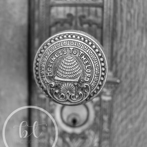 May include: A black and white photo of a vintage door knob with a beehive design and the words "Holiness to the Lord" inscribed around the edge.