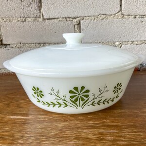 May include: White casserole dish with a lid, featuring a green floral design. The dish has a rounded shape and a smooth, white finish.