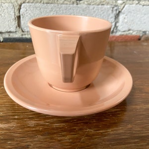 Puede incluir: Un juego de taza y platillo de color rosa p&aacute;lido. La taza tiene un dise&ntilde;o simple y moderno con un borde ligeramente acampanado y una sola asa. El platillo es de forma redonda y simple.