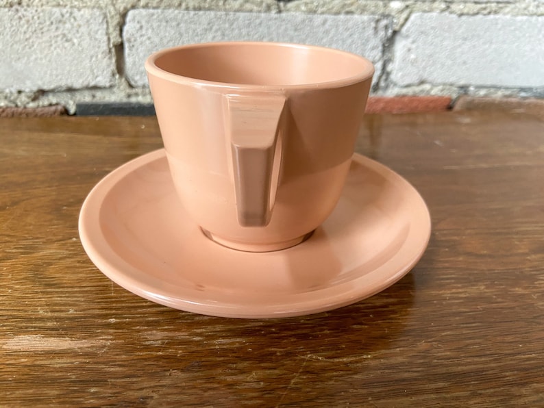Puede incluir: Un juego de taza y platillo de color rosa p&aacute;lido. La taza tiene un dise&ntilde;o simple y moderno con un borde ligeramente acampanado y una sola asa. El platillo es de forma redonda y simple.