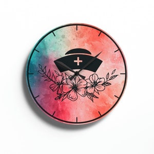 May include: A watercolor clock with a pink, blue, and orange background. The clock face features a black silhouette of a nurse's hat with a cross on top, surrounded by floral designs.