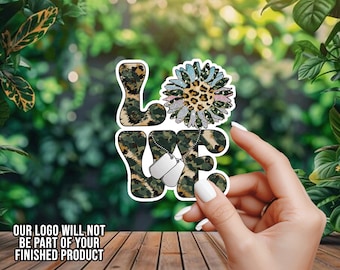 May include: A sticker with the word "LOVE" in a camouflage pattern, with a sunflower design replacing the "O". Two dog tags hang from the "E". The text "OUR LOGO WILL NOT BE PART OF YOUR FINISHED PRODUCT" is at the bottom.