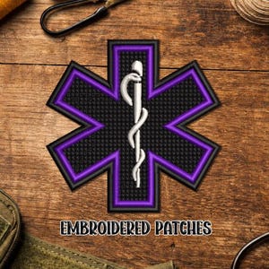 May include: Embroidered patch featuring a black star of life design with a purple border and a white staff of Hermes. The patch has the words "EMBROIDERED PATCHES" in a brown font. The patch is on a wooden surface.