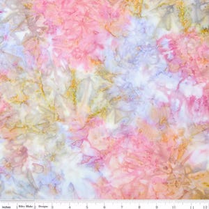 May include: A fabric with a watercolor-like design. The pattern features a blend of pink, white, gold, and blue hues. The fabric is measured with a ruler in inches, with the text "Riley Blake Designs" visible.