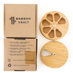 Puede incluir: Un organizador de pastillas de bambú con tapa y caja. El organizador redondo tiene siete compartimentos, cada uno etiquetado para un día de la semana. La caja es marrón y presenta el texto "Bamboo Vault" e instrucciones.