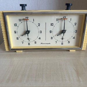 May include: A white ceramic mug with a black handle and the text "But First, Coffee" in a bold, black font. The mug is set against a blurred background, suggesting a cosy setting.