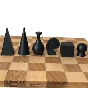 Op de afbeelding: Een houten schaakbord met zes zwarte geometrische vormen: een piramide, een kegel, een vaas, een spiraal, een kubus en een bol. Het bord heeft een lichtbruin en tan geruit patroon. De vormen zijn in een rij gerangschikt.
