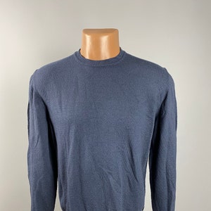 Puede incluir: Un suéter azul oscuro de manga larga con cuello redondo.