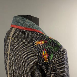 May include: A blue and white checked jacket with a red trim and embroidered flowers on the shoulder.