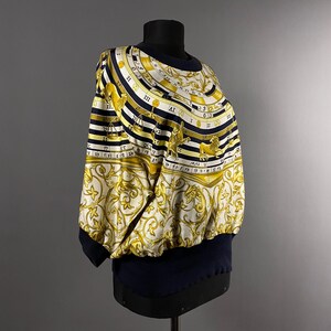 May include: A long-sleeved shirt with black and white stripes and a gold and white zodiac print. The print features the zodiac signs and Roman numerals.