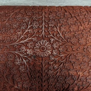 Puede incluir: Una caja de madera con intrincados tallados florales. La caja est&aacute; hecha de madera marr&oacute;n oscura y tiene un dise&ntilde;o rico y detallado. Los tallados son de estilo tradicional y presentan una variedad de flores y hojas.