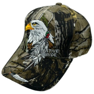May include: A camouflage baseball cap with an embroidered eagle and feathers. The cap has the text "NATIVE PRIDE" on the front.