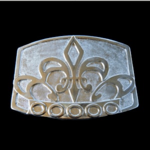 May include: Silver-toned belt buckle featuring a fleur-de-lis design and a row of six round accents.
