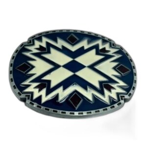 May include: Oval-shaped belt buckle with a geometric design. The buckle features a dark blue border and a central pattern in cream and dark blue, with small red diamond accents. The metal has a silver finish.