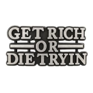 May include: A rectangular, silver-colored pin with the phrase "GET RICH OR DIE TRYIN" in bold, capital letters. The text is set against a dark gray background, with horizontal lines separating the words. The pin has a slightly raised, three-dimensional appearance.