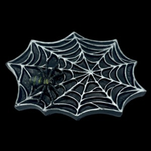 Op de afbeelding: Een zwarte en zilveren Halloween-decoratie met een spin en een spinnenweb. De spin is zwart met groene en gele accenten. Het web is zilverkleurig en de basis is zwart, tegen een zwarte achtergrond.
