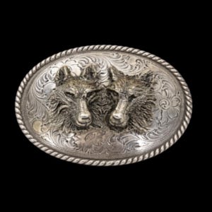 May include: Oval silver-toned belt buckle featuring two wolf heads. The buckle has a detailed floral and scroll design around the wolf heads and a rope-like border. The wolves are in a 3D relief, with intricate fur details.