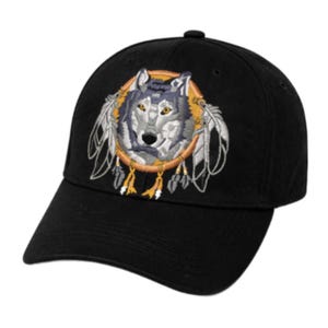 Könnte beinhalten: Schwarze Baseballkappe mit einem gestickten Wolfsdesign in einem Traumfänger. Der Wolf hat graues und weißes Fell mit gelben Augen. Der Traumfänger ist orange mit weißen Federn und gelben Quasten. Eine klassische, verstellbare Kappe.