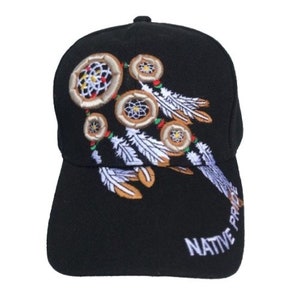 Puede incluir: Gorra de béisbol negra con un diseño bordado de un atrapasueños con plumas y cuentas. El texto "NATIVE PRIDE" está bordado en el lateral de la gorra.
