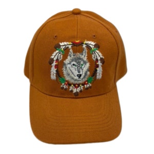 May include: A brown baseball cap featuring an embroidered design of a wolf's head surrounded by feathers and beads.