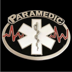 Op de afbeelding: Een zilveren gesp met een zwarte achtergrond en een witte ster van het leven met een slang en een staf. De woorden "PARAMEDIC" staan in een zilveren boog boven de ster. Een rode EKG-lijn bevindt zich aan beide kanten van de ster.