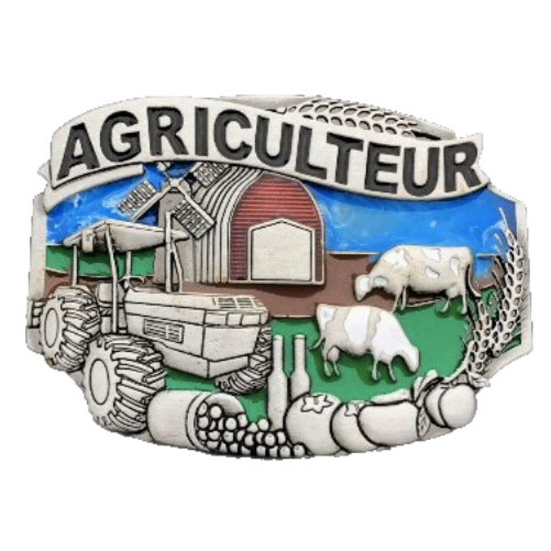 Op de afbeelding: Een zilverkleurige metalen gesp met het woord "AGRICULTEUR" bovenaan. De gesp toont een tractor, schuur, windmolen, koeien en landbouwproducten. De achtergrond heeft blauwe en groene accenten.