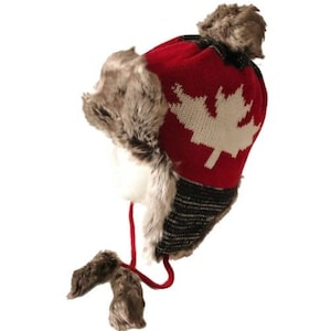 May include: Red knit winter hat with a white maple leaf design and faux fur ear flaps and pom poms.