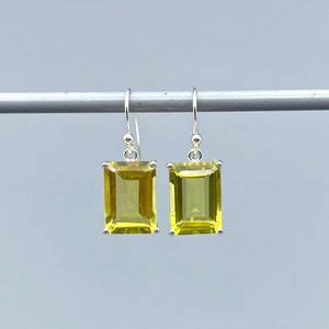 May include: A pair of silver drop earrings with rectangular, faceted, yellow gemstones.