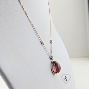 Op de afbeelding: Een ketting met een roze edelsteen hanger, een ros&eacute;gouden ketting en zilveren accenten. De hanger heeft de vorm van een traan met een gefacetteerde edelsteen.