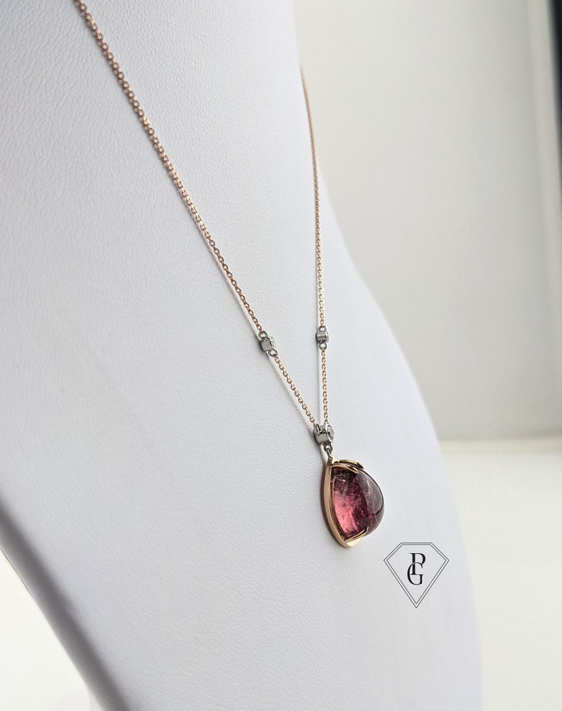 Op de afbeelding: Een ketting met een roze edelsteen hanger, een ros&eacute;gouden ketting en zilveren accenten. De hanger heeft de vorm van een traan met een gefacetteerde edelsteen.
