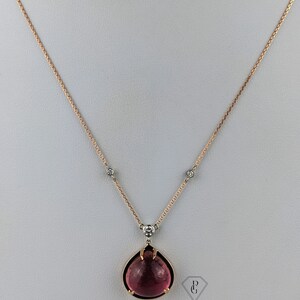 Op de afbeelding: Een delicate ketting van ros&eacute;goud met een hanger van roze edelsteen. De hanger heeft de vorm van een traan met een gefacetteerde edelsteen en kleine diamant accenten.
