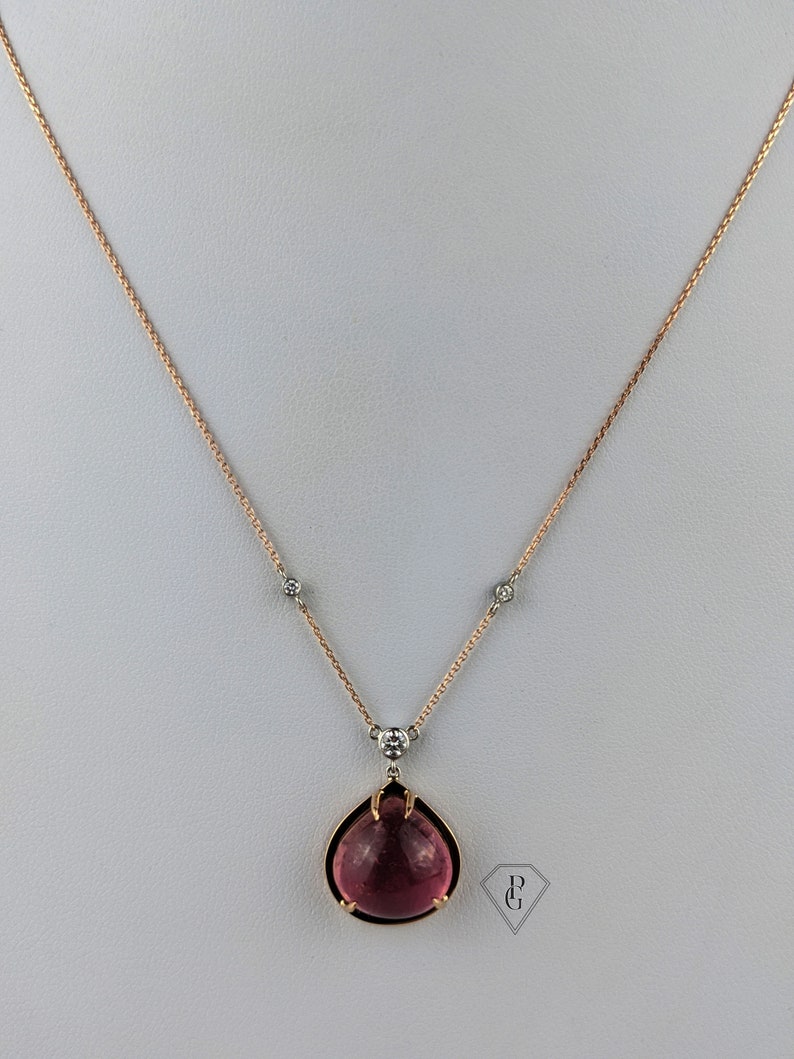Op de afbeelding: Een delicate ketting van ros&eacute;goud met een hanger van roze edelsteen. De hanger heeft de vorm van een traan met een gefacetteerde edelsteen en kleine diamant accenten.
