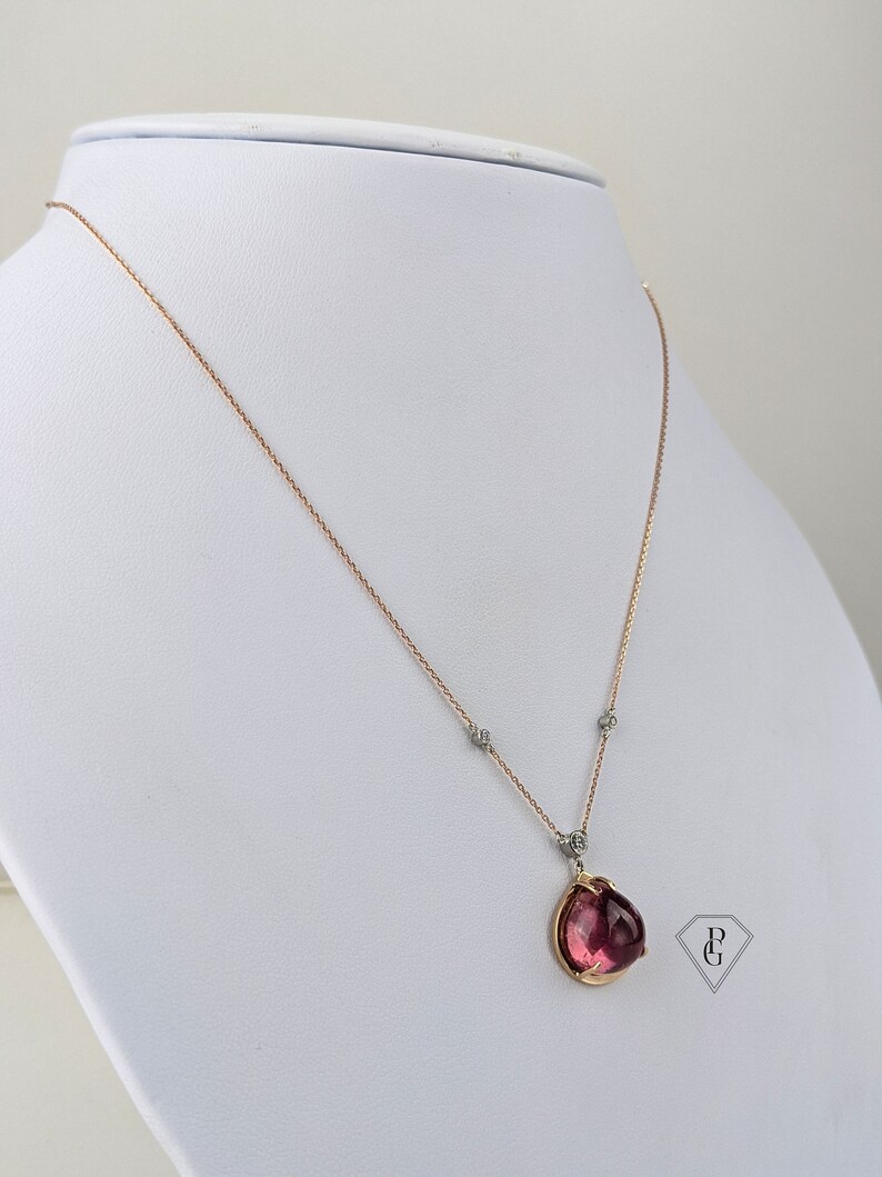 Op de afbeelding: Een ketting van ros&eacute;goud met een hanger van roze edelsteen en kleine diamant accenten. De hanger is gezet in een gouden setting en heeft een delicaat, vrouwelijk ontwerp.