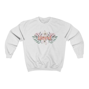 Pu&ograve; includere: Felpa bianca con la scritta "tired" in corallo, circondata da un design floreale con fiori rosa e bianchi e foglie verdi. La felpa &egrave; realizzata in un materiale morbido.