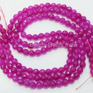 May include: A strand of pink faceted gemstone beads. The beads are round and have a smooth, polished finish. Beads Gems India is printed on a white label.