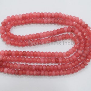 Puede incluir: Una hebra de cuentas de piedra preciosa facetadas de color rosa. Las cuentas son pequeñas y redondas, y están enhebradas en un cordón fino. Las cuentas son todas del mismo tamaño y forma, y están dispuestas en un patrón simétrico.