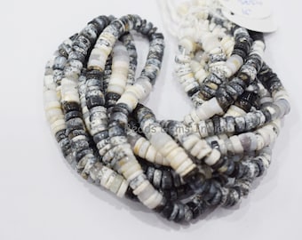 May include: A strand of white and black opal beads. The beads are round and have a speckled pattern. The beads are strung on a white cord.
