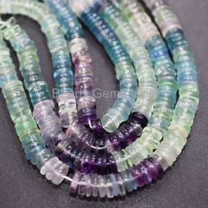 May include: A strand of multi-colored fluorite beads. The beads are faceted and have a variety of shades of green, blue, and purple. The beads are strung on a clear thread.