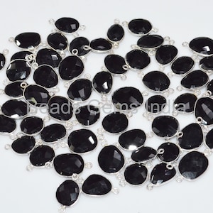 May include: A group of black gemstone pendants with silver jump rings. The gemstones are faceted and have a smooth, polished finish. The jump rings are attached to the top of each gemstone.
