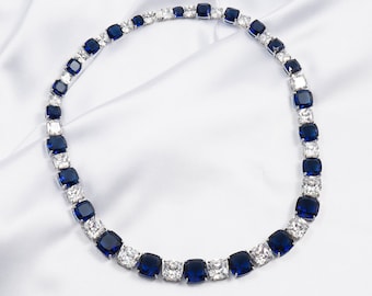 May include: A silver necklace with alternating blue and clear square-shaped stones.