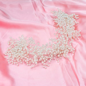 May include: A delicate pearl hairpiece with a floral design. The hairpiece is made of small white pearls and silver wire, and it is arranged in a cascading pattern. The hairpiece is perfect for a wedding or other special occasion.